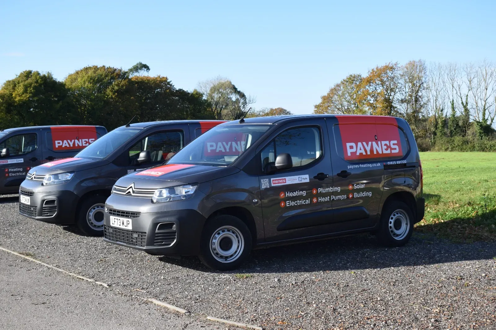 Three Paynes diesel vans parked in a row on gravel with fields behind