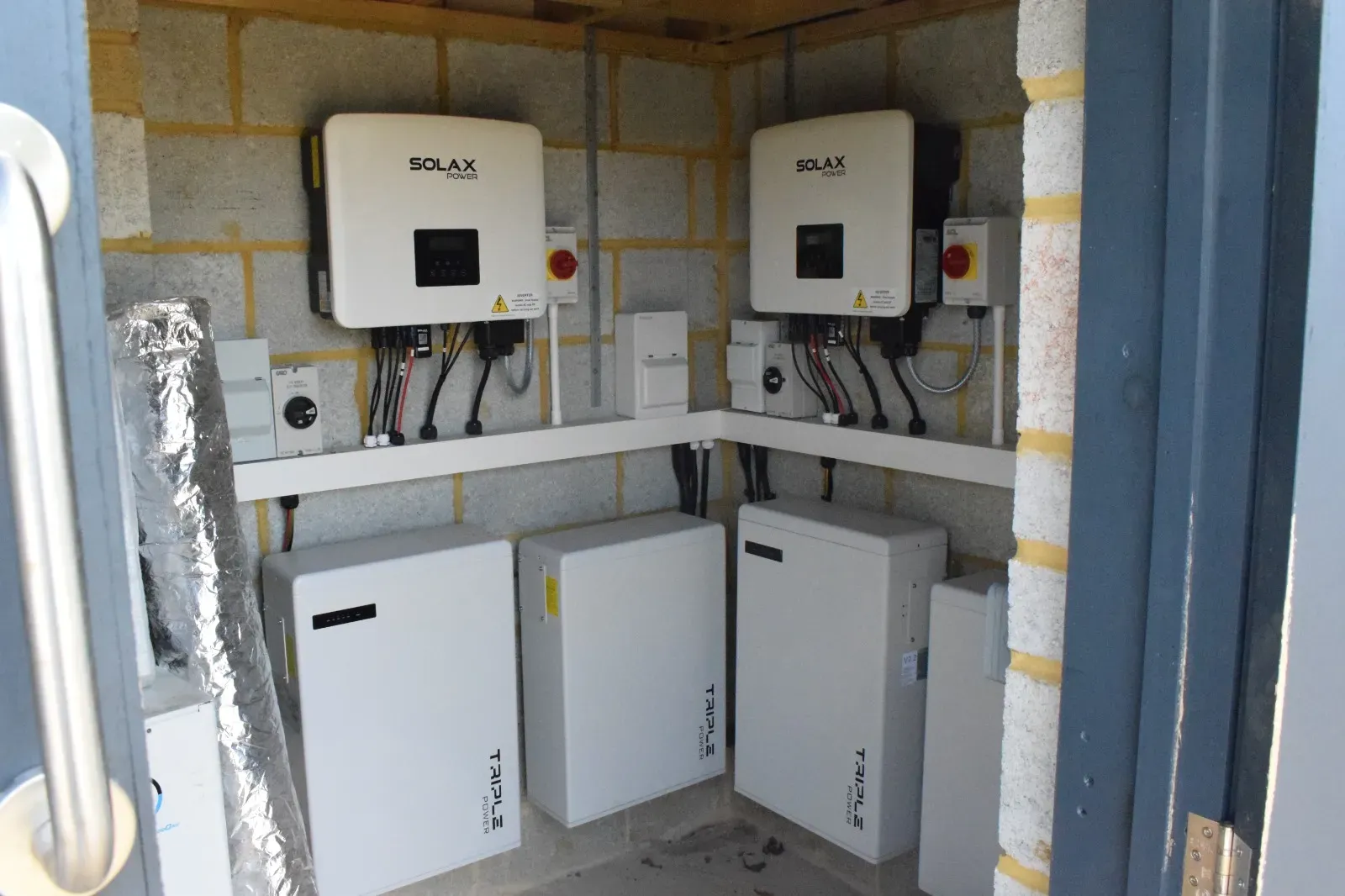 Electrical equipment and battery inverters neatly mounted on a garage wall with labelled cabling