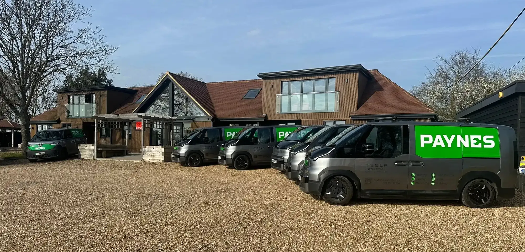 Paynes vans parked in front of the timber-clad Oak Tree Barn office with a tree overhead