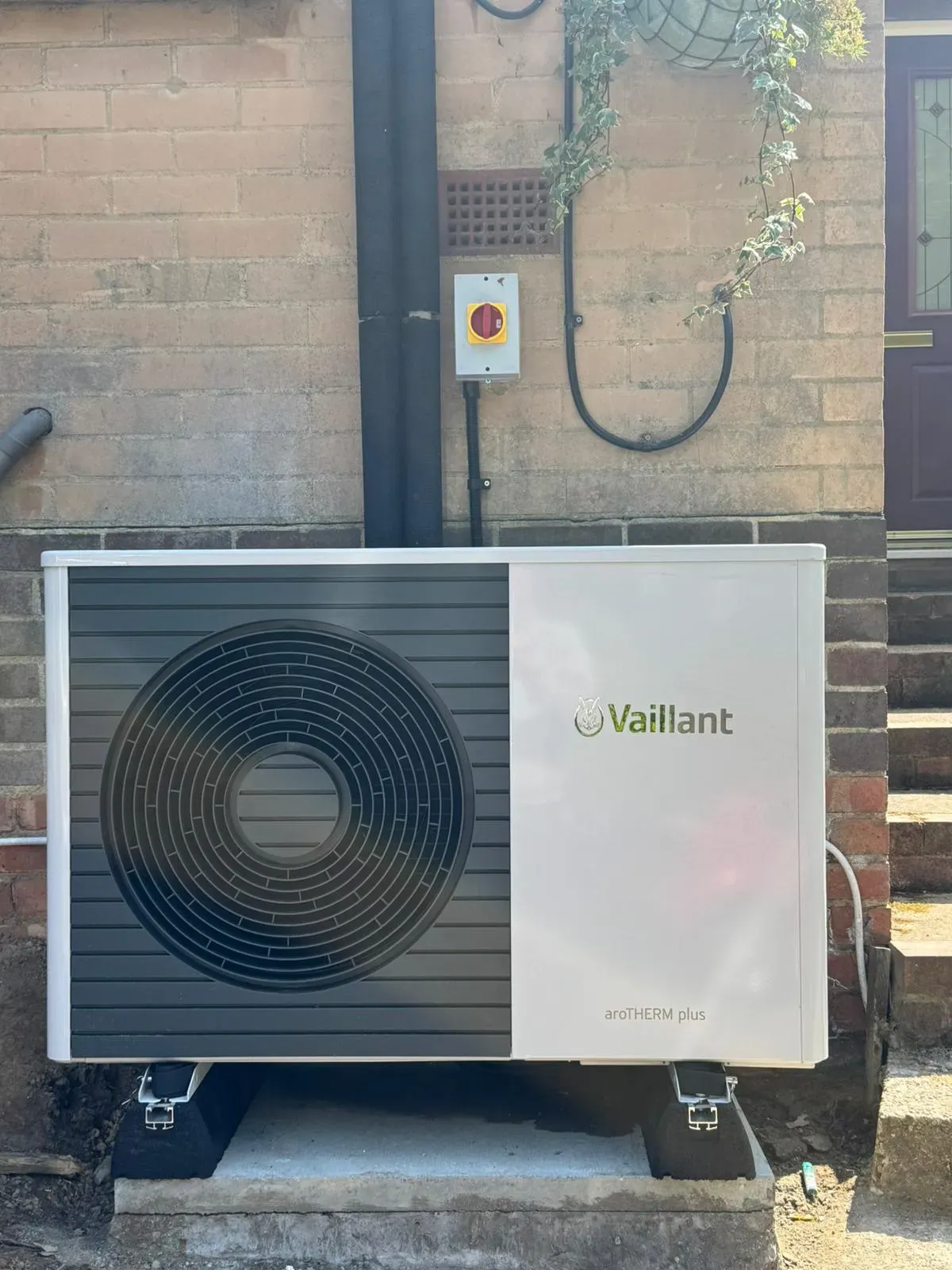 An air-source heat pump outdoor unit mounted on a house wall
