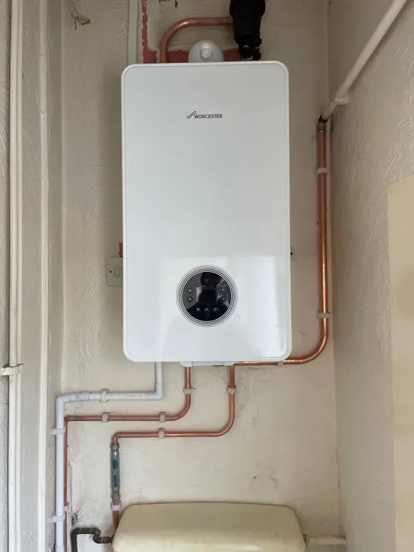 A wall-mounted boiler in a utility room with the flue and condensate pipe run to the outside wall